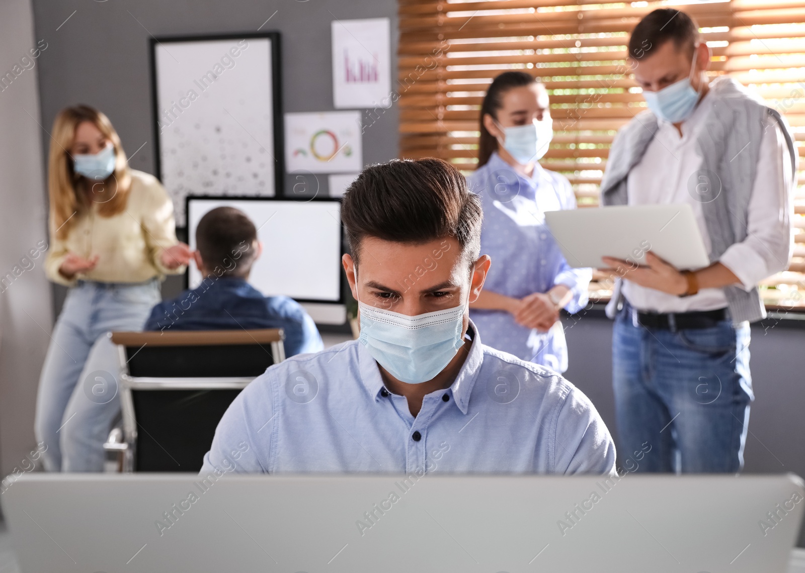 Photo of Worker with mask in office. Protective measure during COVID-19 pandemic