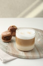 Aromatic coffee in cup and tasty macarons on white wooden table