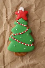 Photo of Christmas tree shaped gingerbread cookie on crumpled parchment, top view