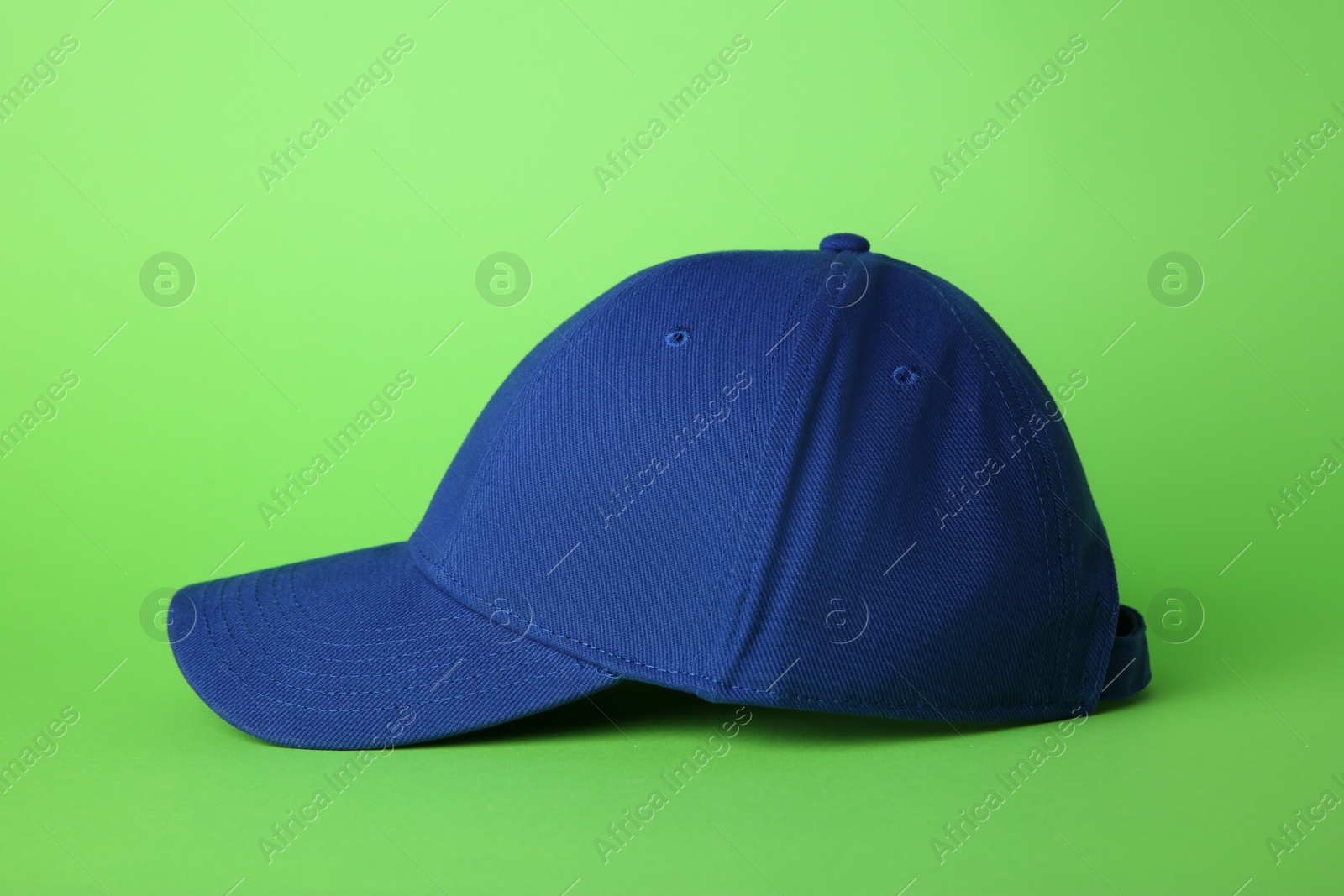 Photo of Stylish blue baseball cap on light green background