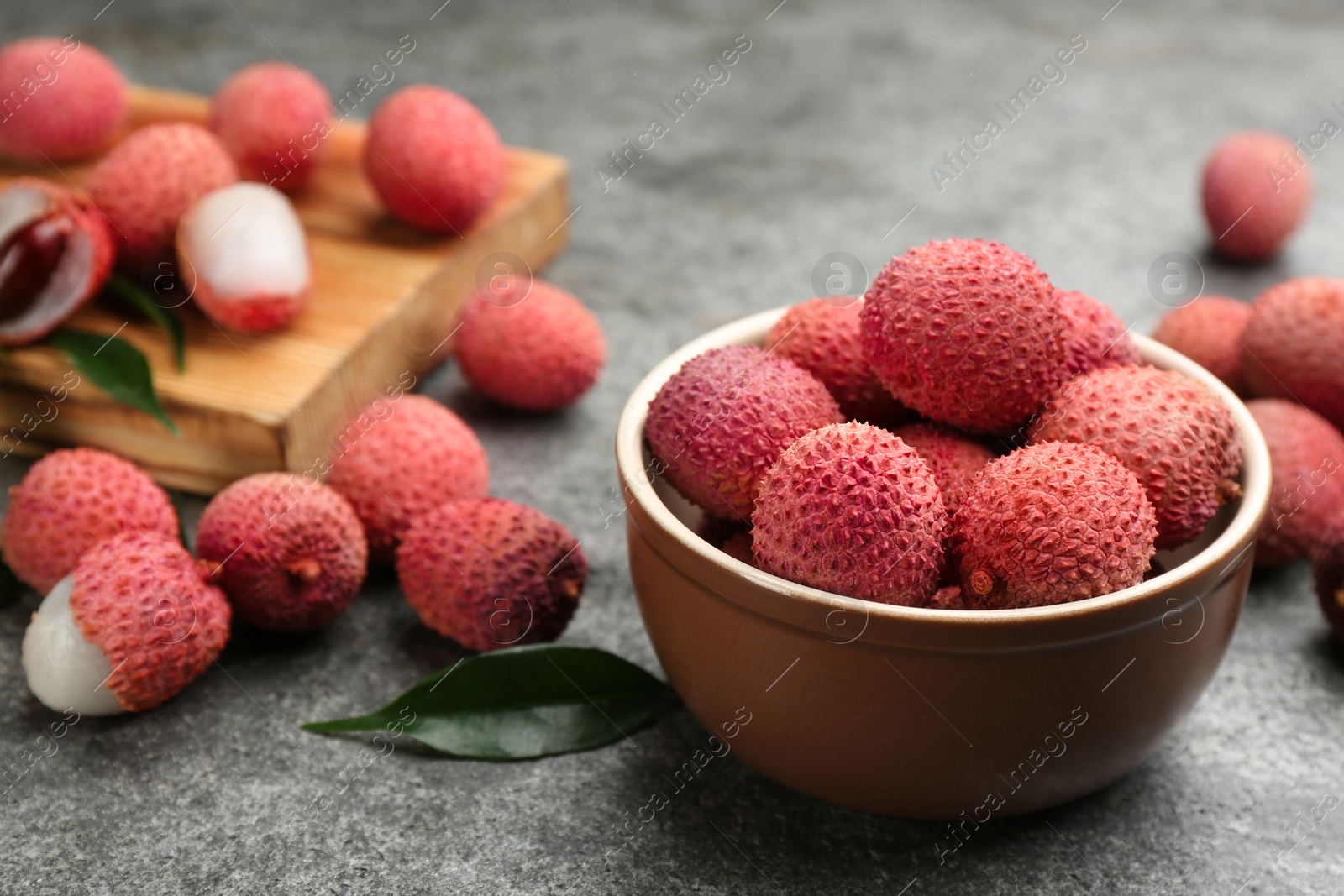 Photo of Fresh ripe lychee fruits in bowl on grey table