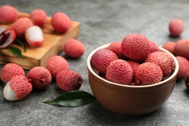 Fresh ripe lychee fruits in bowl on grey table