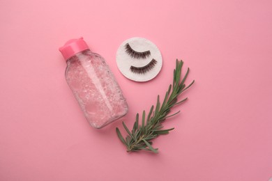 Photo of Bottle of makeup remover, cotton pad, rosemary and false eyelashes on pink background, flat lay