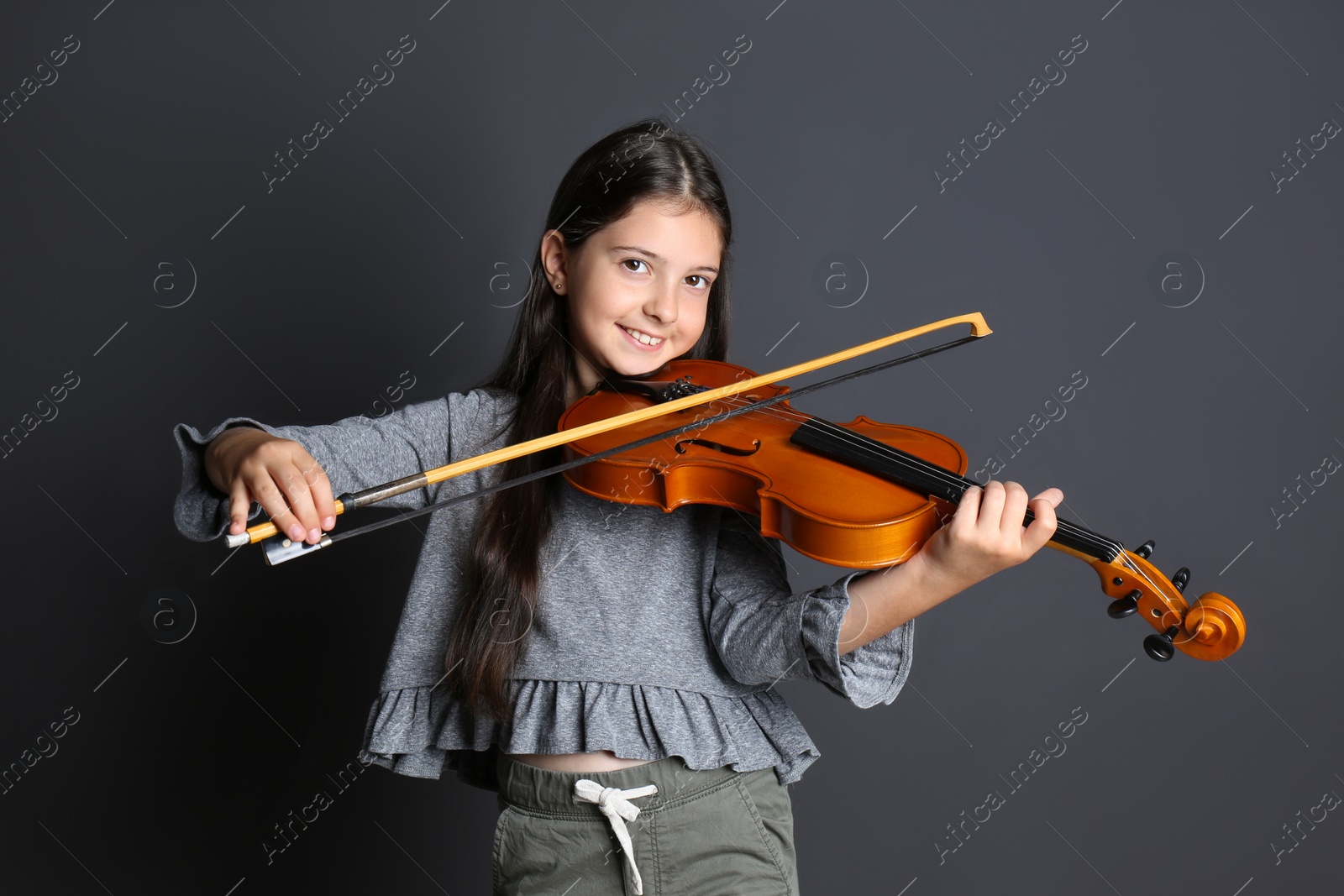 Photo of Preteen girl playing violin on black background