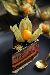 Photo of Piece of tasty cake decorated with physalis fruit on table, closeup
