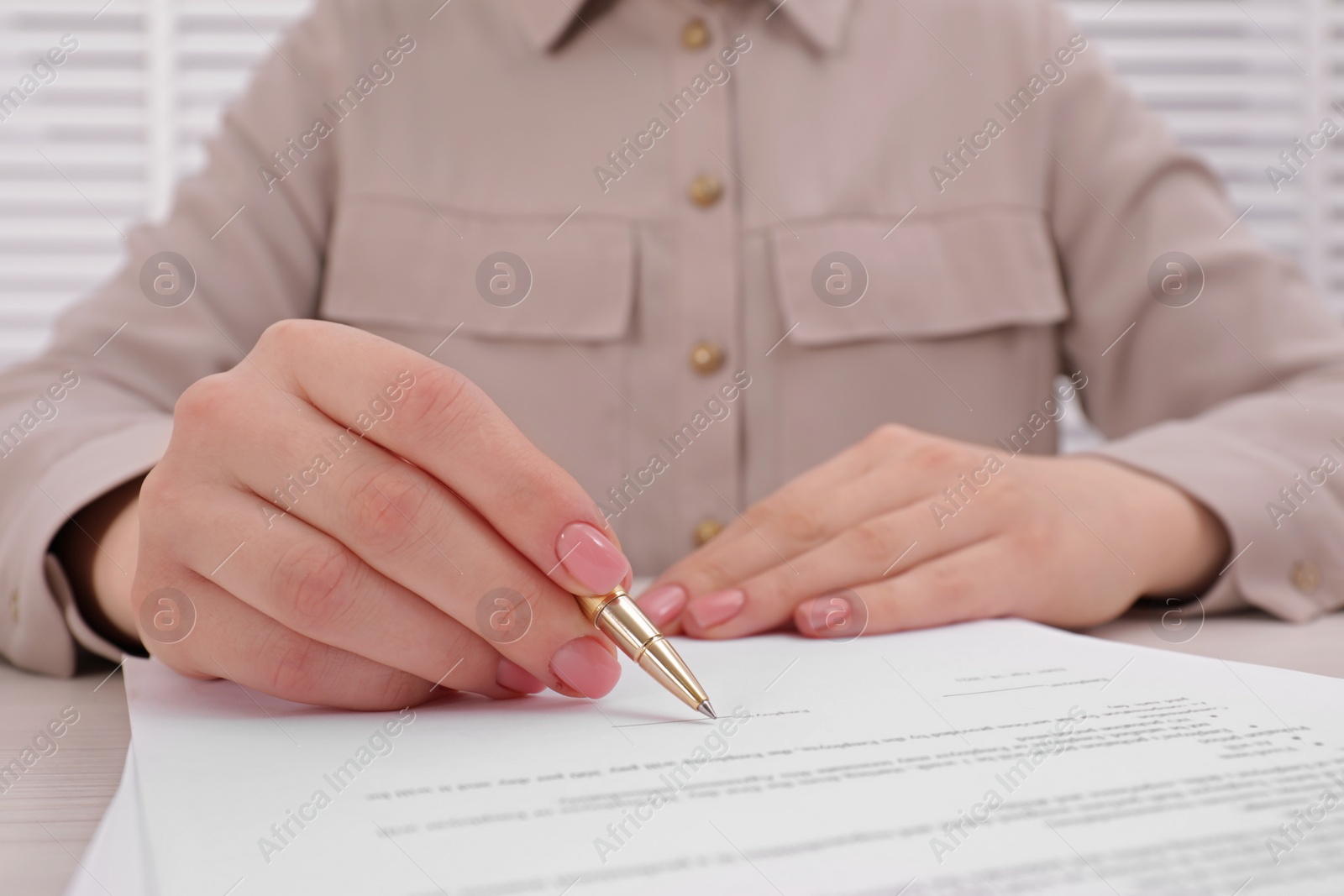 Photo of Woman signing document at table, closeup view