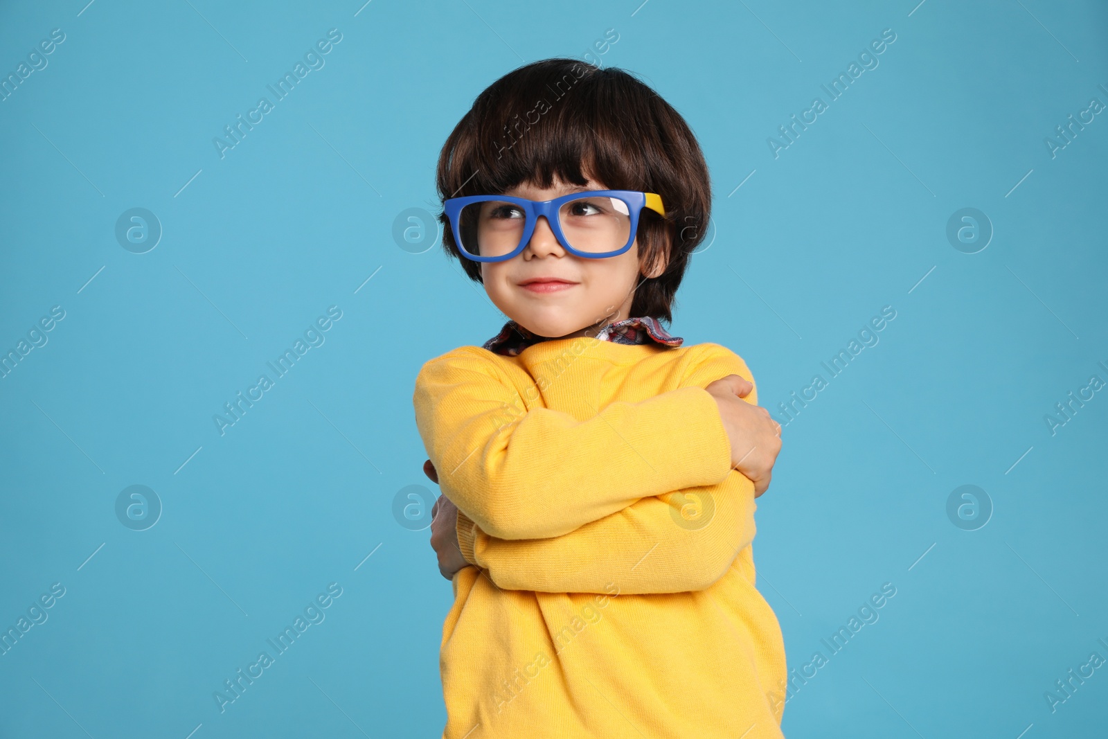 Photo of Cute little boy with funny glasses on light blue background