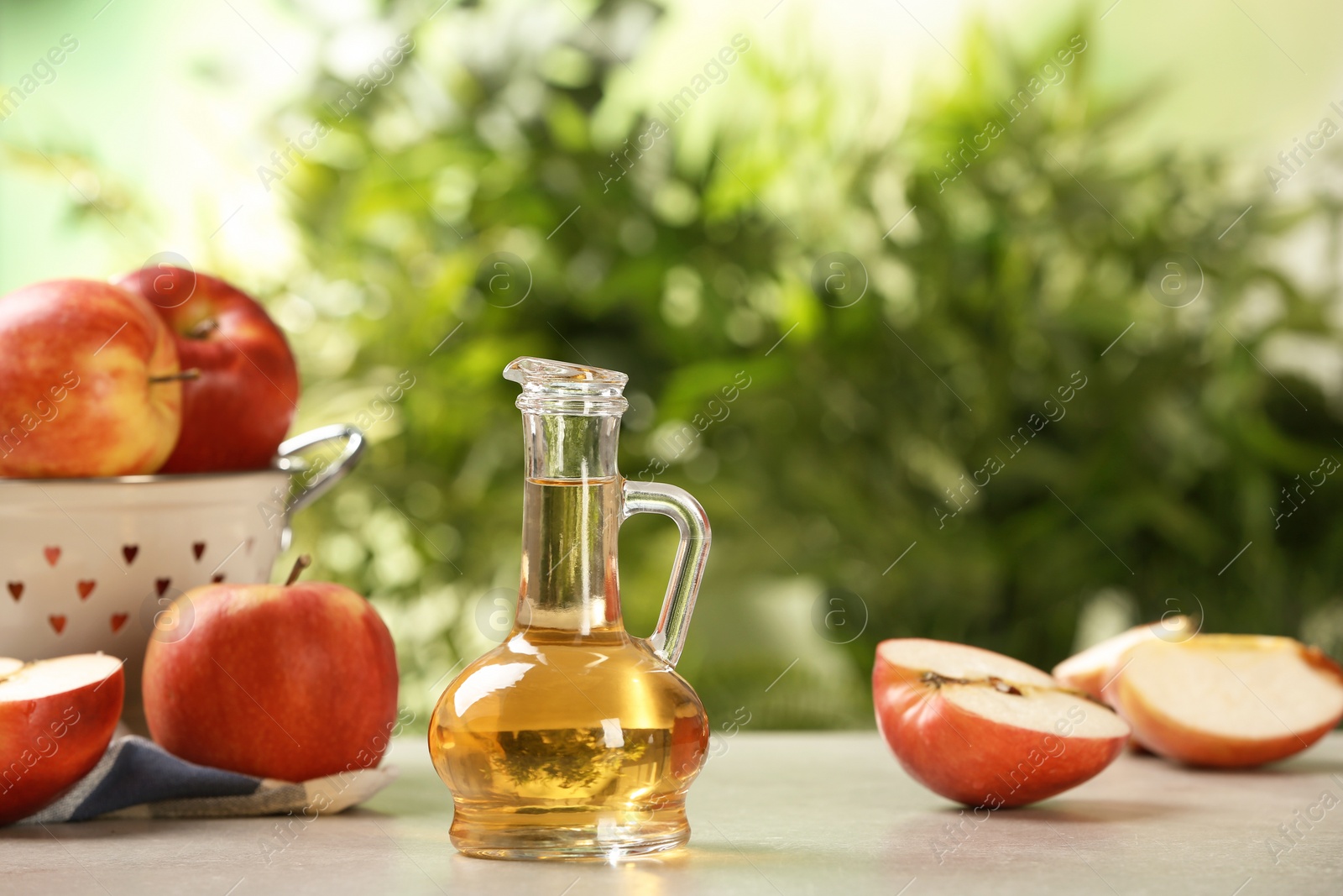 Photo of Composition with jug of apple vinegar on table. Space for text