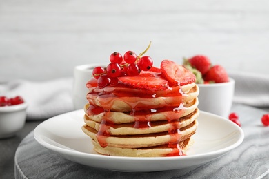 Delicious pancakes with fresh berries and syrup on table