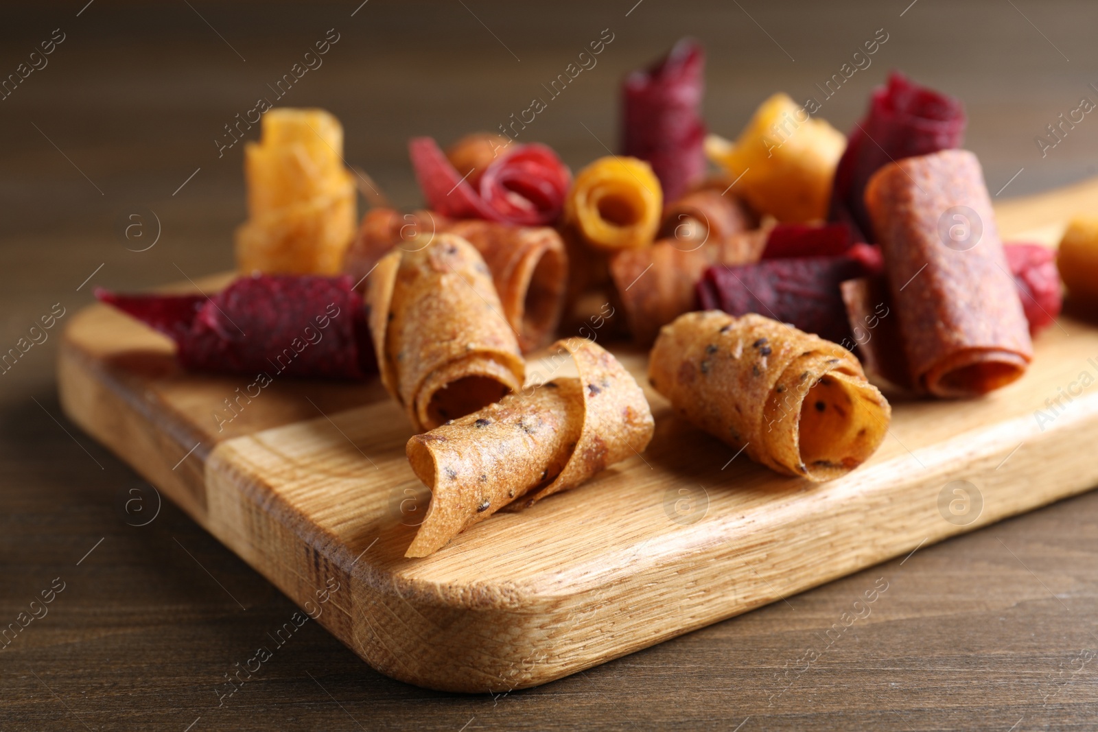 Photo of Delicious fruit leather rolls on wooden table, closeup