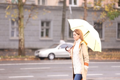 Woman with umbrella in city on autumn rainy day