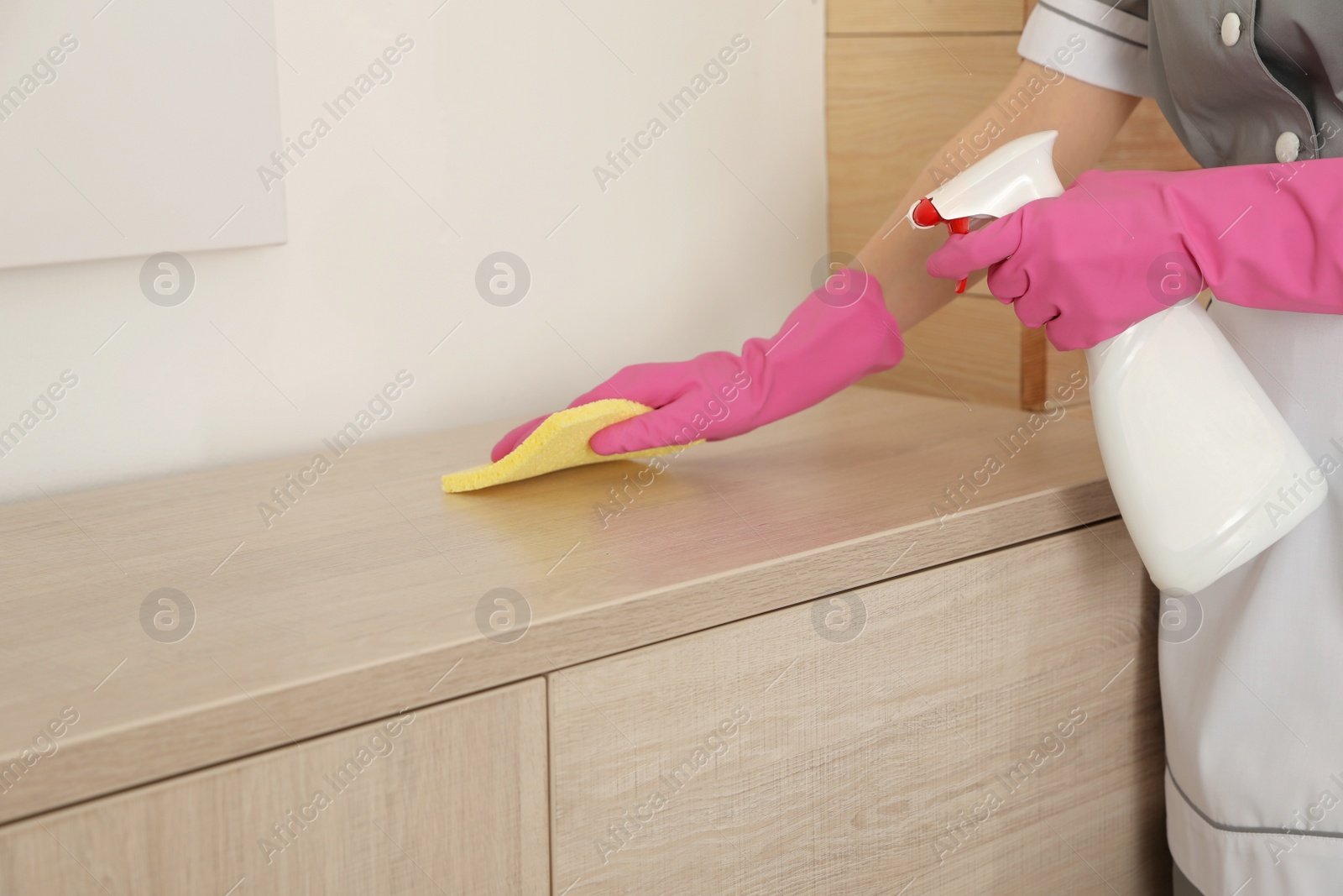 Photo of Young chambermaid wiping dust with rag in hotel room, closeup. Space for text