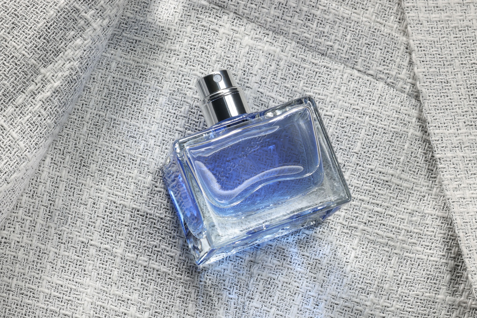 Photo of Luxury men's perfume in bottle on grey jacket, above view