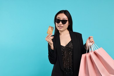 Photo of Smiling woman with shopping bags and credit card on light blue background. Space for text