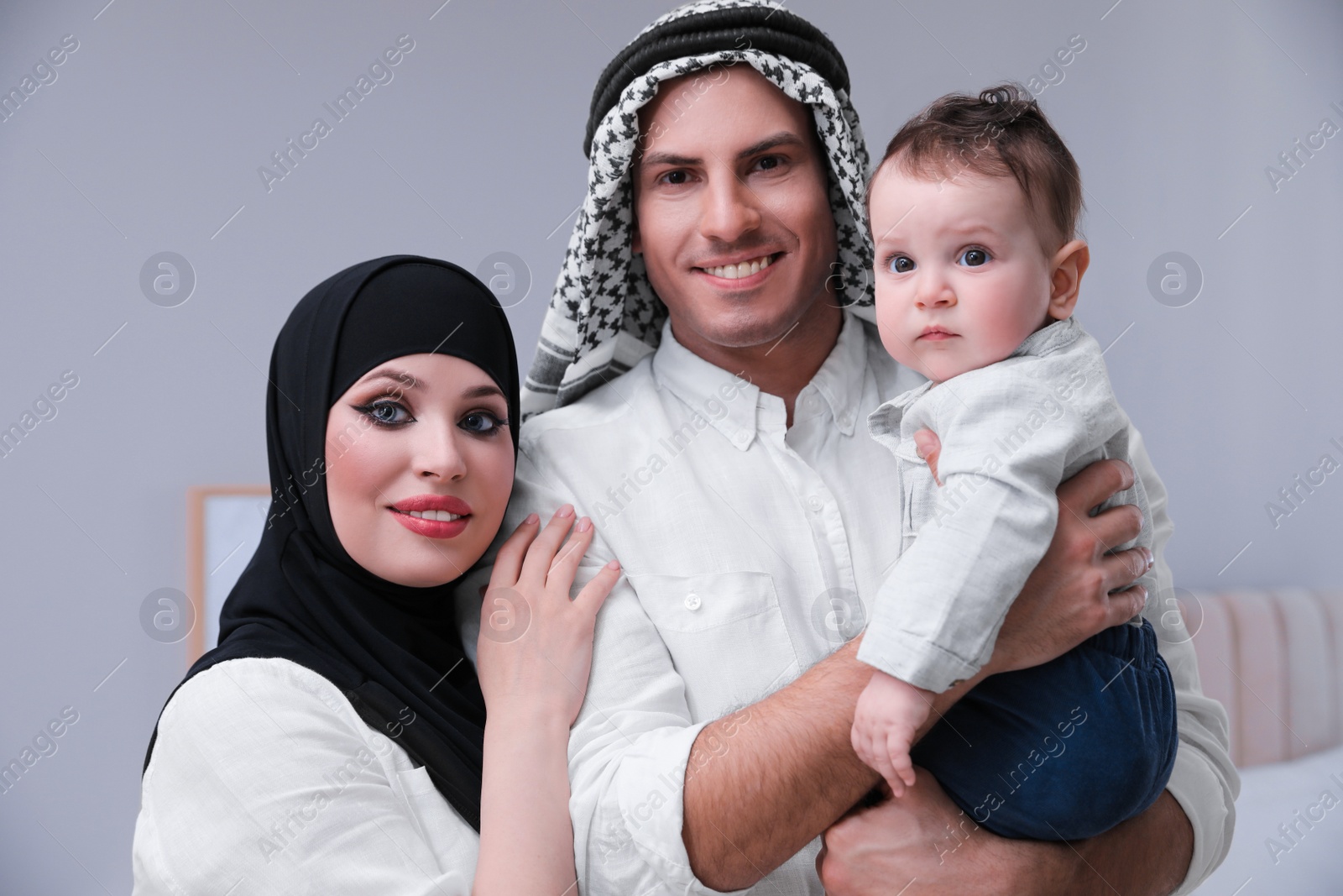 Photo of Happy Muslim family with little son in bedroom