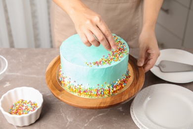 Photo of Woman decorating fresh delicious birthday cake in kitchen, closeup