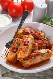 Photo of Delicious stuffed cabbage rolls cooked with homemade tomato sauce on table, closeup