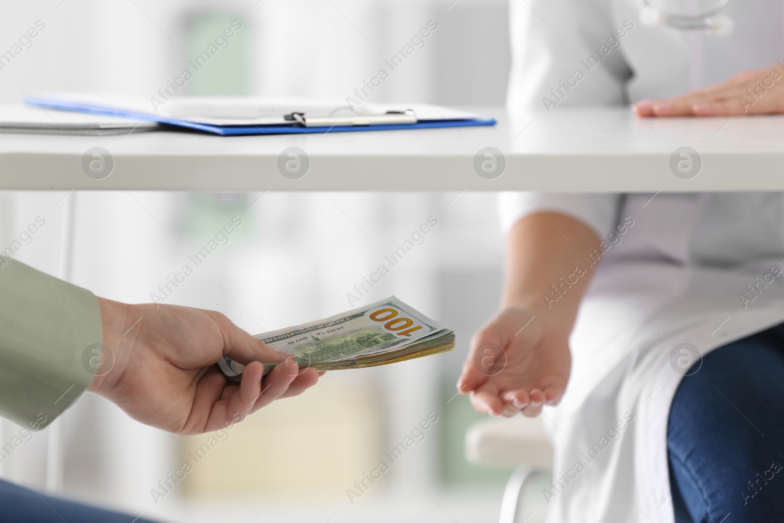 Photo of Patient giving bribe to doctor under table in clinic, closeup. Corrupted medicine