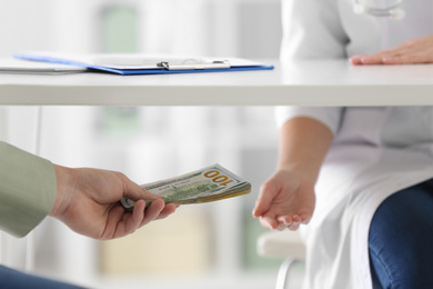 Patient giving bribe to doctor under table in clinic, closeup. Corrupted medicine