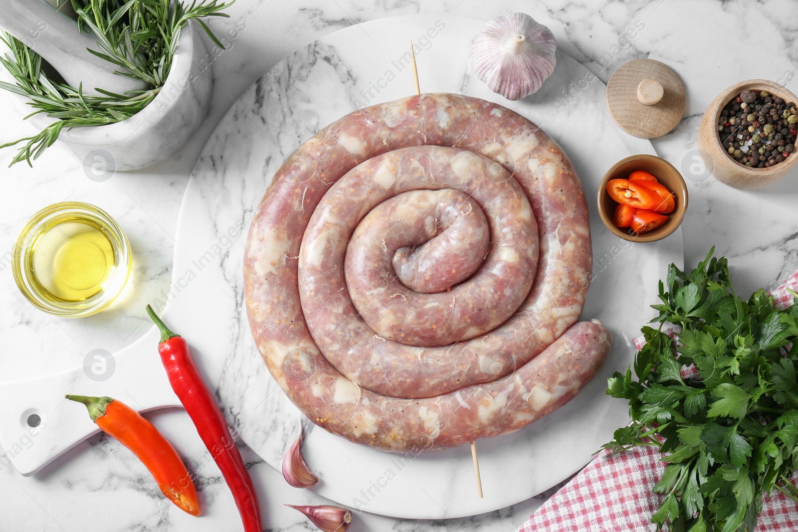 Photo of Raw homemade sausage, spices and other products on white marble table, flat lay