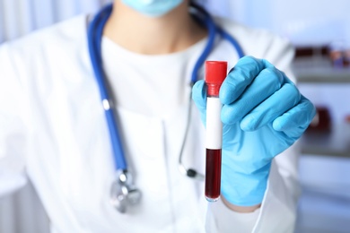 Laboratory worker holding test tube with blood sample for analysis, closeup