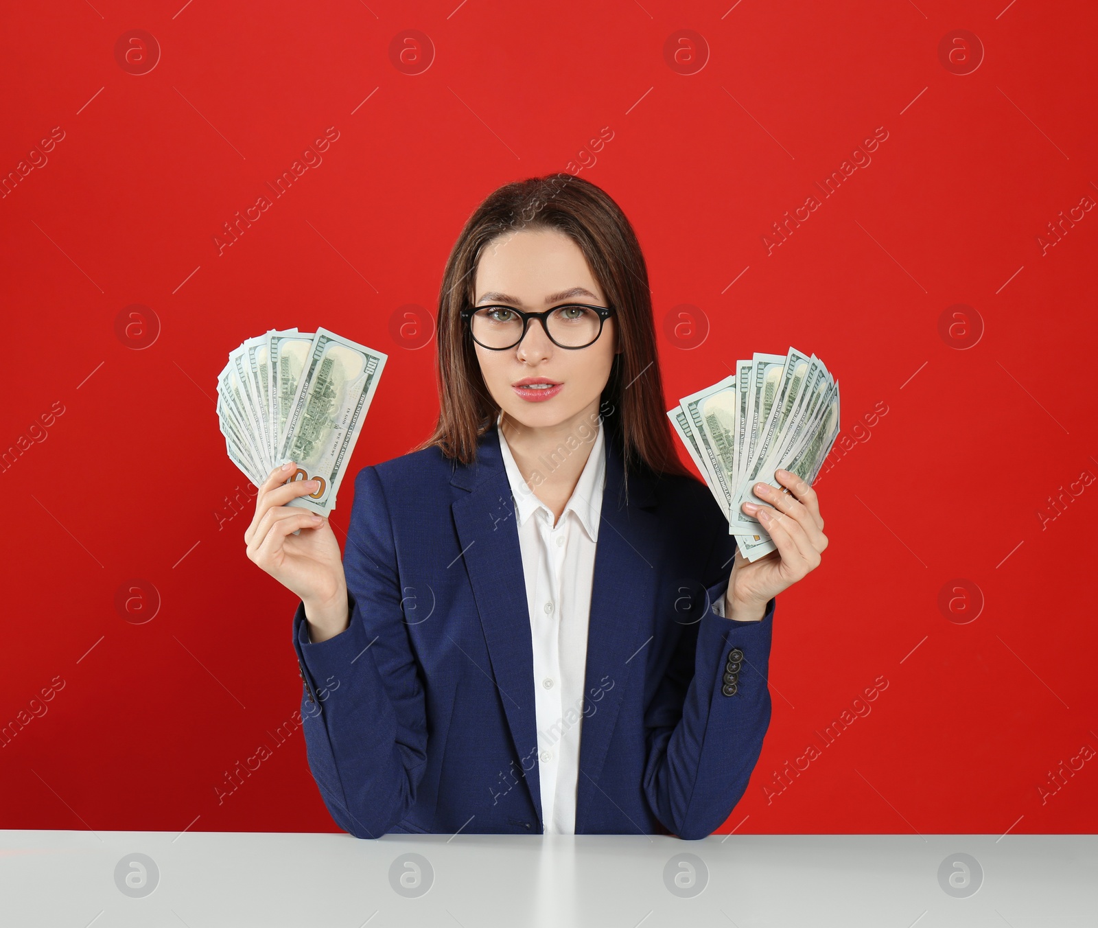 Photo of Young woman with money at table on crimson background