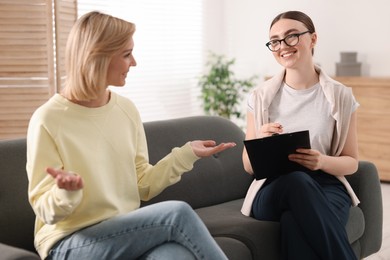 Photo of Professional psychotherapist working with on sofa patient in office