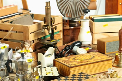 Photo of Many different items on wooden table indoors. Garage sale