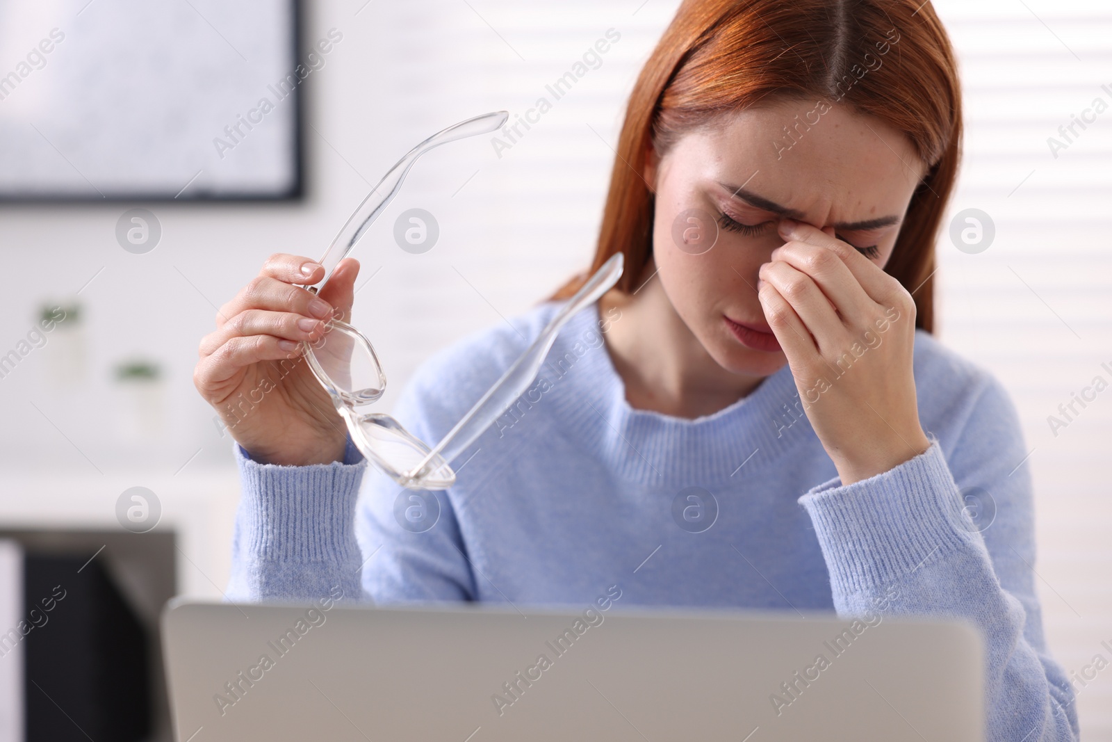 Photo of Woman with glasses suffering from headache at workplace in office