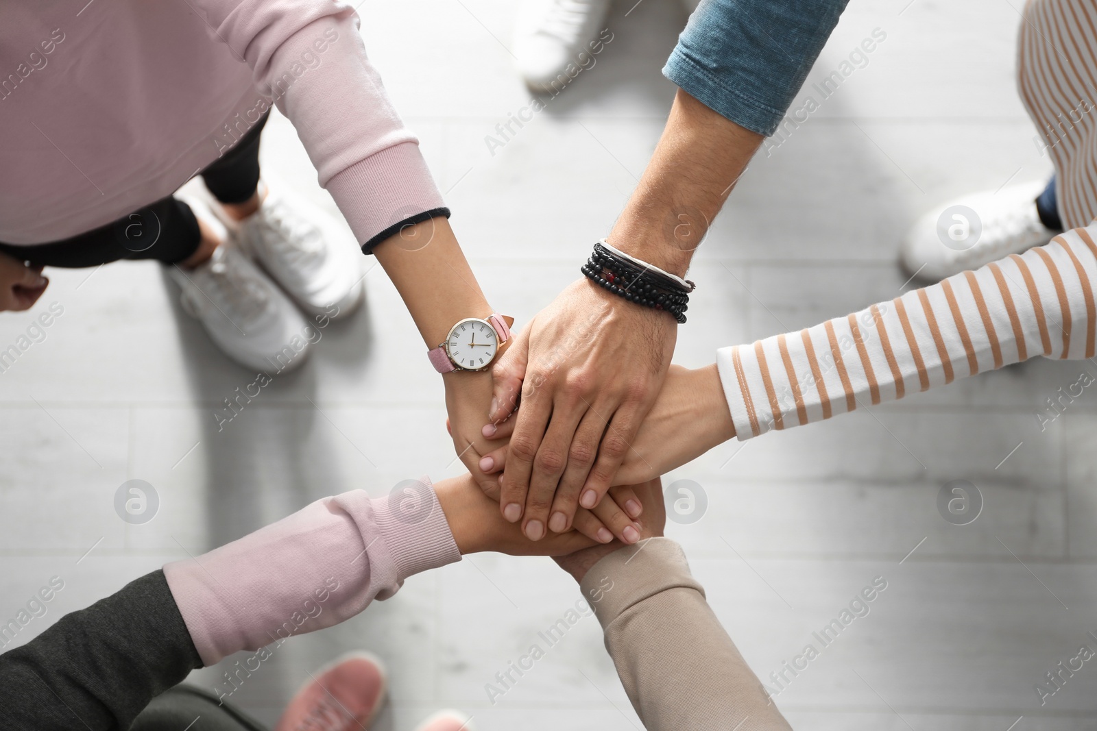 People holding hands together over light wooden background, top view. Unity concept Photo of People holding hands together over light wooden background, top view. Unity concept