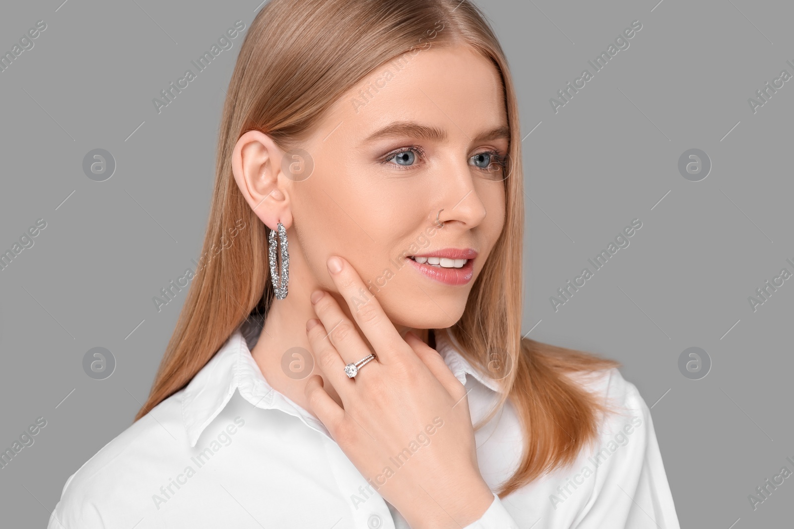 Photo of Beautiful young woman with elegant jewelry on gray background