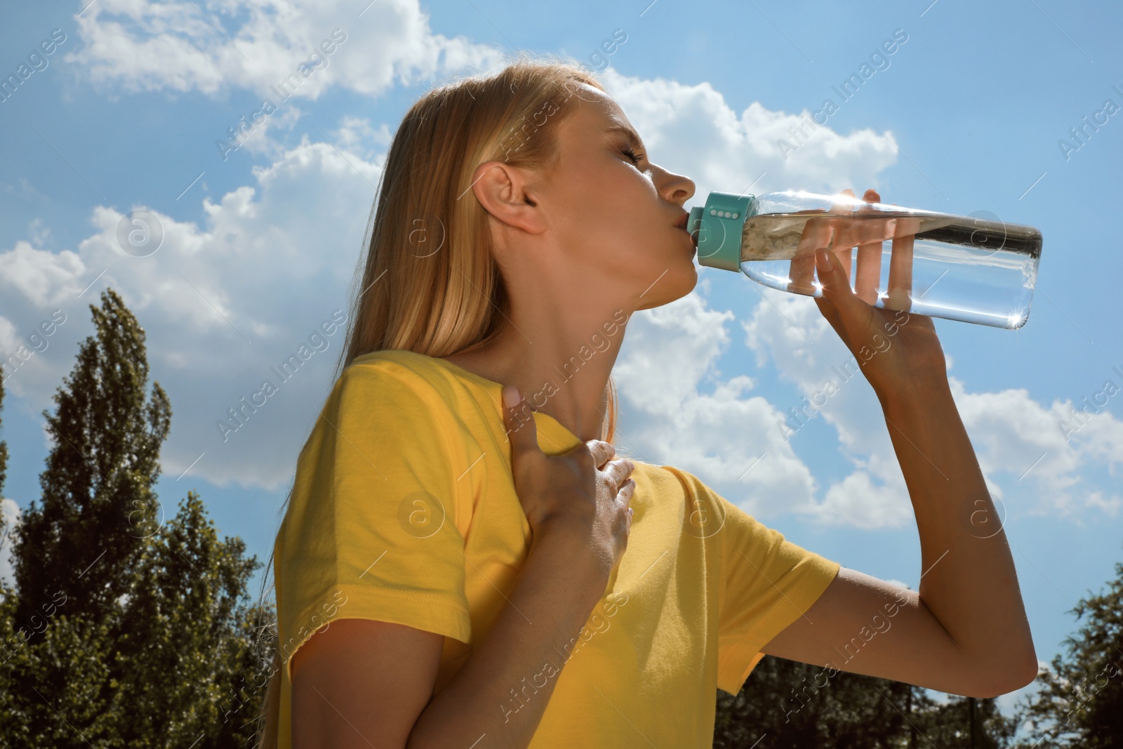 Photo of Woman drinking water to prevent heat stroke outdoors