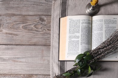 Photo of Bible, willow branches and church candle on wooden table, flat lay. Space for text
