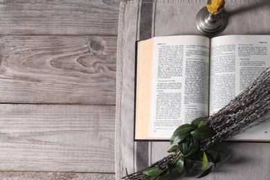 Bible, willow branches and church candle on wooden table, flat lay. Space for text