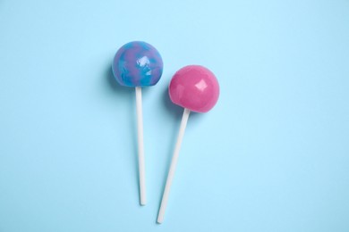 Photo of Sticks with colorful lollipops on light blue background, flat lay