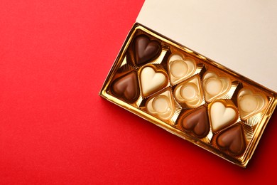 Photo of Partially empty boxchocolate candies on red background, top view. Space for text