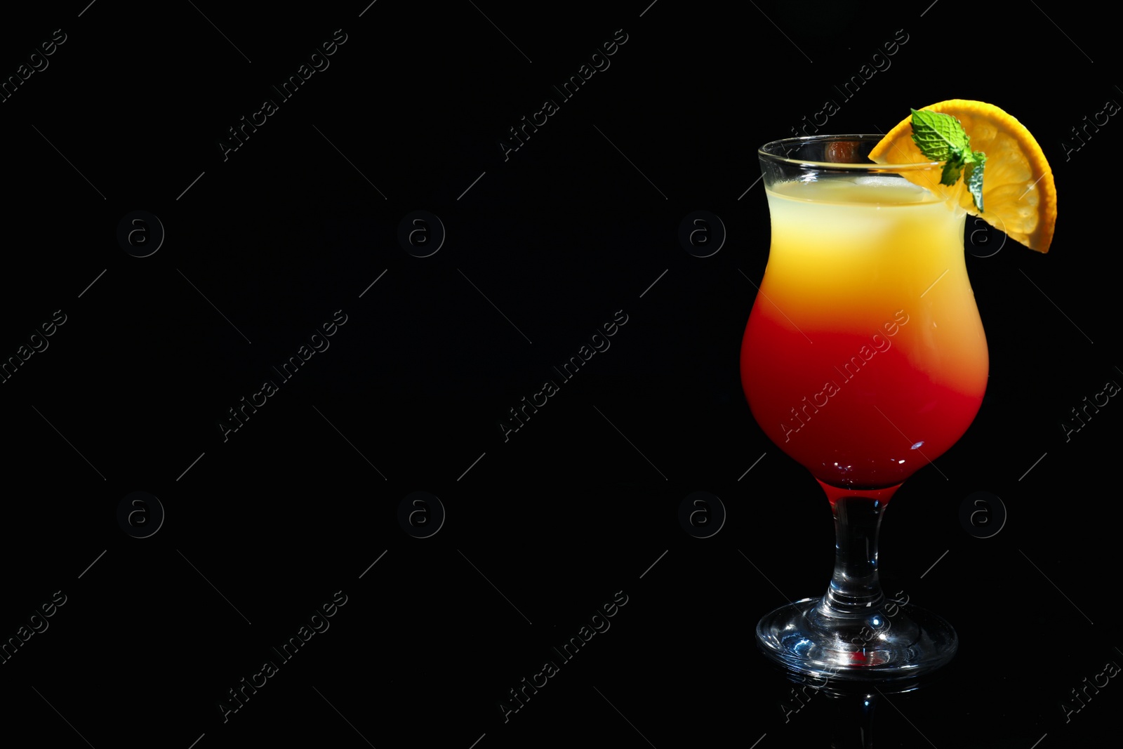 Photo of Glass of delicious cocktail Sex on the Beach decorated with orange and mint against black background. Space for text