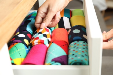 Photo of Woman opening drawer with different colorful socks indoors, closeup