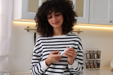 Photo of Diabetes. Woman using lancet pen in kitchen