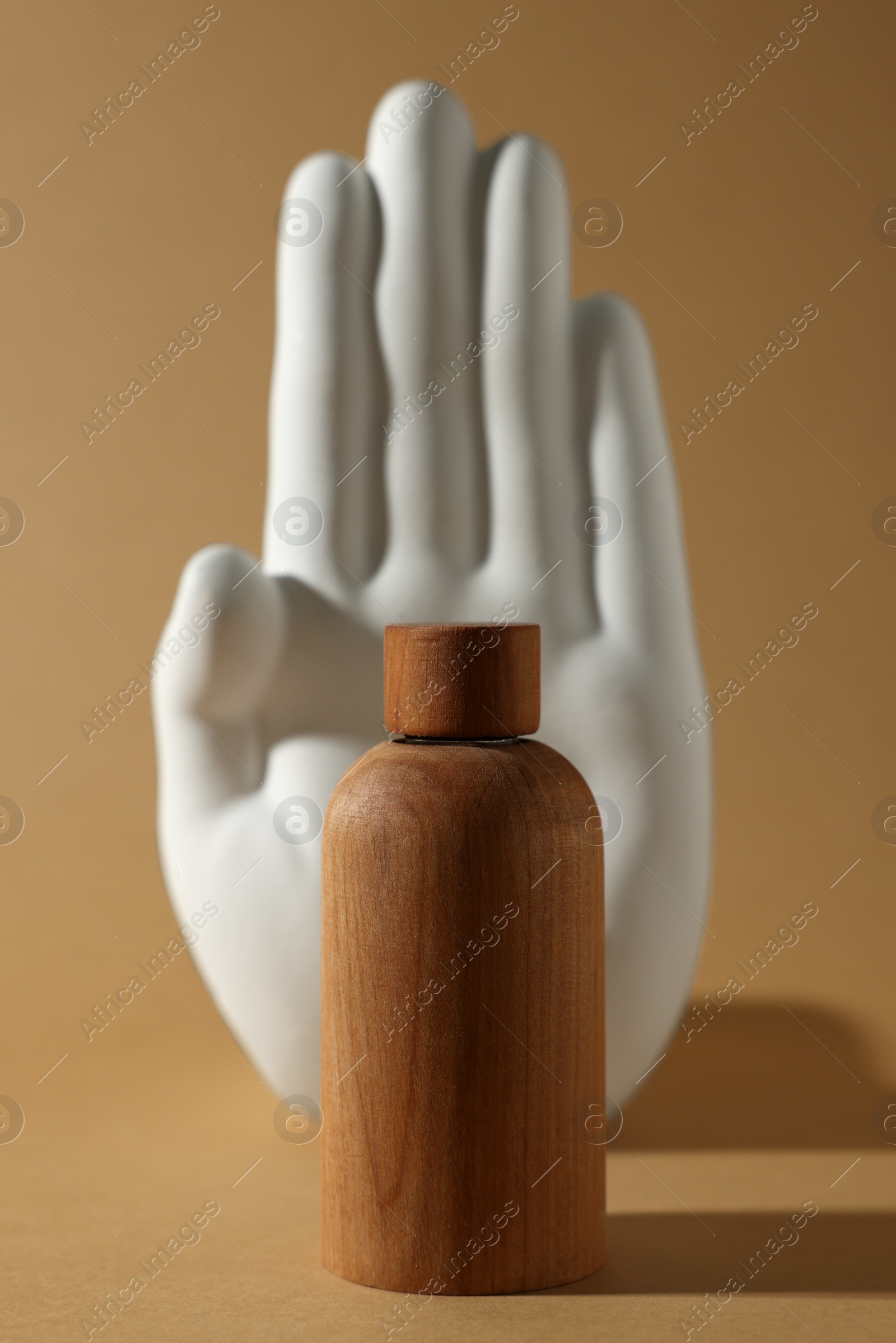 Photo of Composition with wooden bottle of cosmetic product on dark beige background