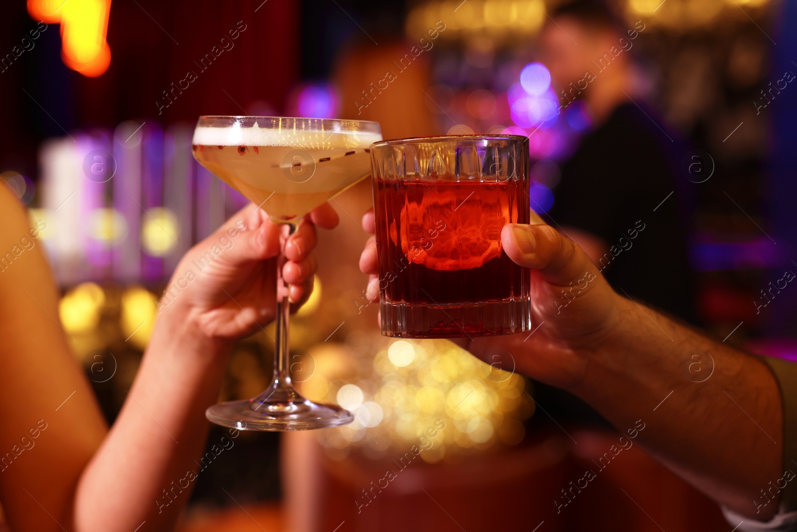 Photo of People clinking glasses with fresh cocktails in bar, closeup