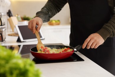 Photo of Man cooking dish on cooktop in kitchen, closeup