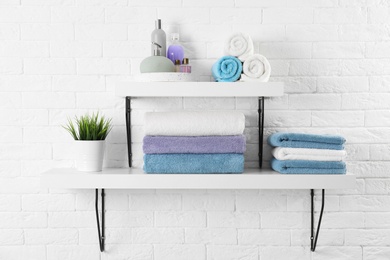 Photo of Shelves with clean towels and toiletries on brick wall