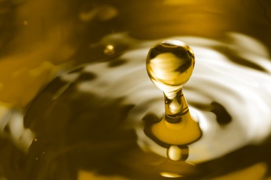 Splash of golden oily liquid with drop as background, closeup. Space for text