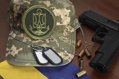 Photo of MYKOLAIV, UKRAINE - SEPTEMBER 26, 2020: Tactical gear and Ukrainian flag on wooden table, closeup