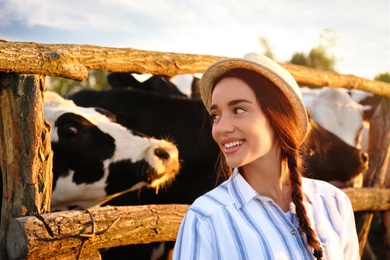 Photo of Young woman near cow pen on farm. Animal husbandry