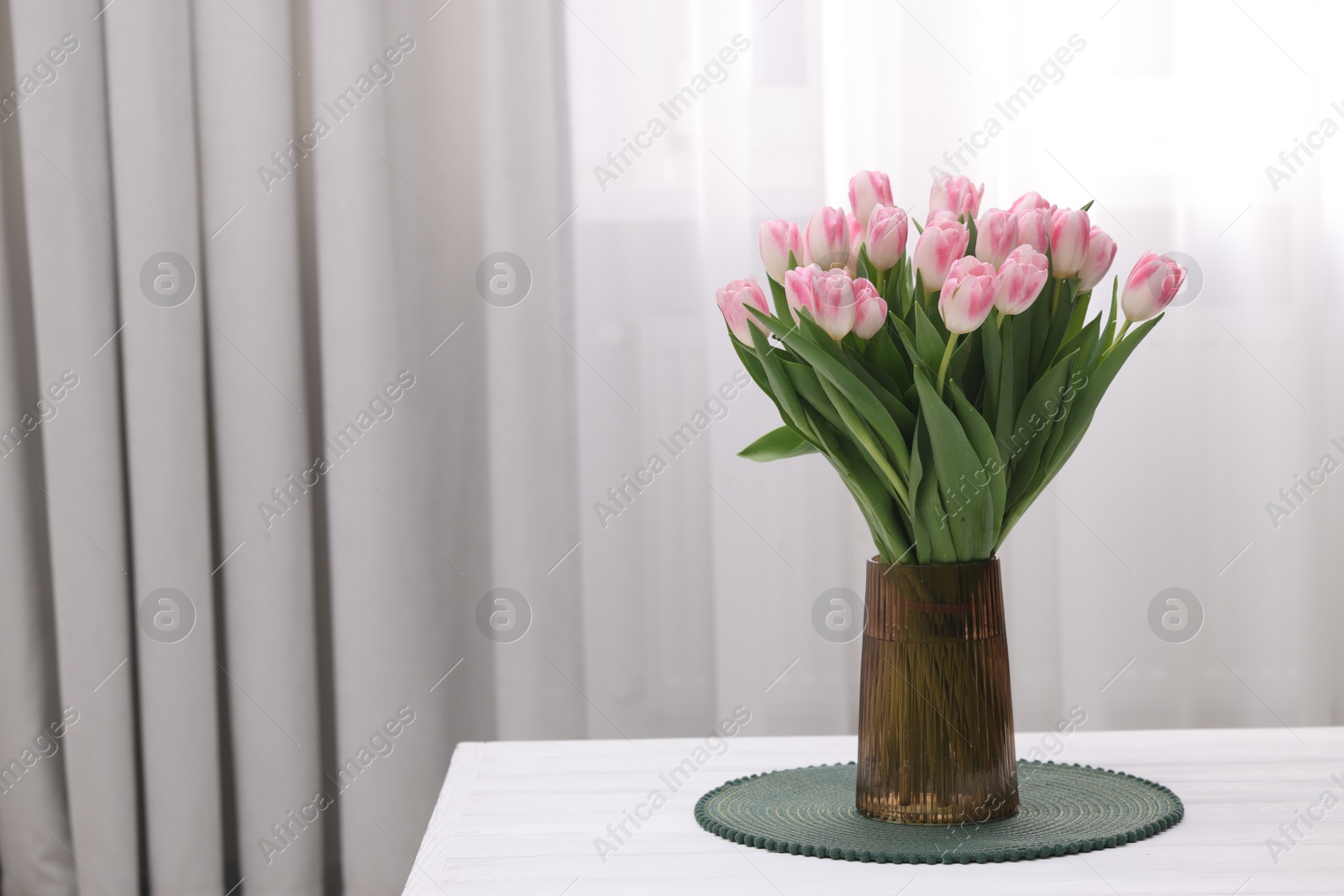 Photo of Beautiful bouquet of fresh pink tulips on table indoors. Space for text