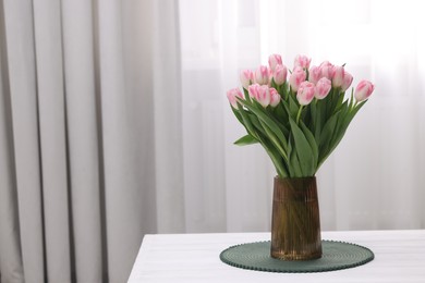 Beautiful bouquet of fresh pink tulips on table indoors. Space for text