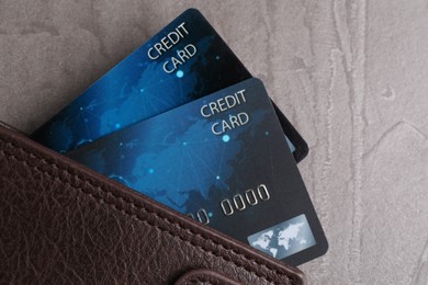 Credit cards in leather wallet on grey textured table, top view