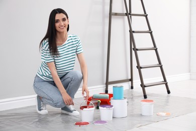 Young woman with decorator's tools near ladder indoors